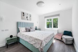 a white bedroom with a bed and a chair at Newly Refurbished 2 Bed Flat in Mill Hill