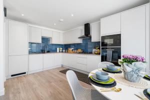 a kitchen with white cabinets and a table with chairs at Newly Refurbished 2 Bed Flat in Mill Hill