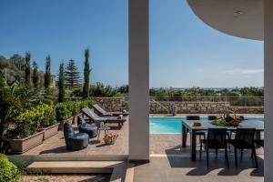 a patio with a table and chairs next to a pool at Villa Ete Premier Luxury Villa by Prime Stay in Stalida