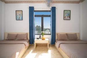 - une chambre avec 2 lits et une fenêtre avec des rideaux bleus dans l'établissement AN Boutique Hotel - STAY 24H, à Đà Lạt