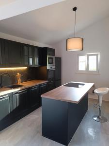 a kitchen with black cabinets and a white counter top at Apartman Lucy in Slatine