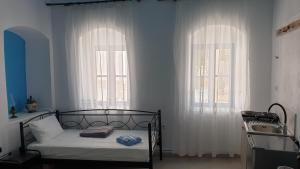 a bedroom with a bed and two large windows at Stathis Apart 2 in Amorgos