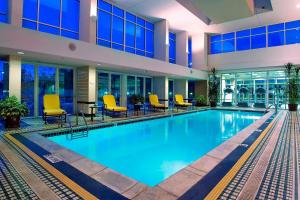 a large swimming pool in a building with yellow chairs at Auburn Hills Marriott Pontiac in Pontiac