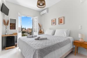 a white bedroom with a bed and a balcony at Villa Kriezi in Spetses