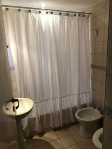 a bathroom with a white shower curtain and a toilet at Departamento quinta sección in Mendoza