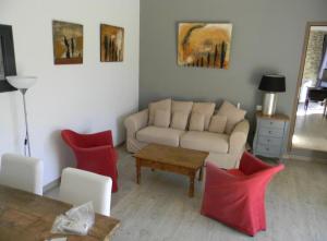 een woonkamer met een bank en rode stoelen bij La Grange de Marie in Valaurie