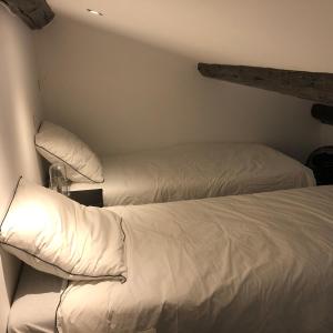 2 bedden in een kamer met witte lakens en kussens bij La Grange de Marie in Valaurie
