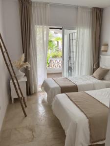 two beds in a hotel room with a window at Boutique apartment 365 - Marbella in Marbella