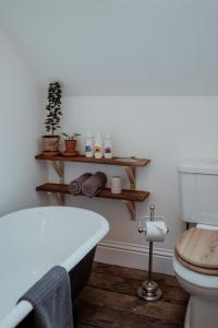 a bathroom with a toilet and a bath tub at Roxie House a cosy farm refurbished Coach House. in Gittisham