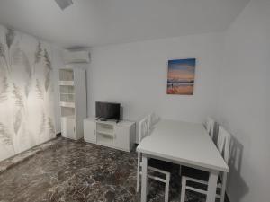 Habitación blanca con mesa y TV. en Vivienda en el centro histórico con ascensor en Jaén