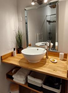 a bathroom with a large white bowl sink on a wooden counter at Le Clos des Roses in Parçay-les-Pins