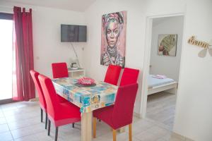 a dining room with a table and red chairs at Apartments Summersong in Novalja