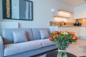 uma sala de estar com um sofá e um vaso de flores sobre uma mesa em Belcasa Mar Suites & Lofts em Middelkerke
