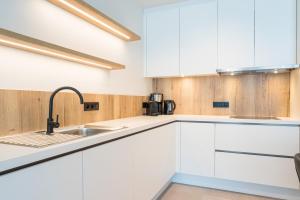 una cocina con armarios blancos y fregadero en Belcasa Mar Suites & Lofts, en Middelkerke