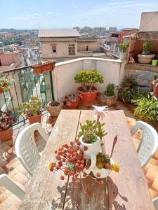 een houten tafel met potplanten op een balkon bij La mansarda dello scultore in Niscemi