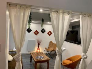 Habitación con cortina, mesa y sillas en Loft Casa Wi hyper centre - Parking-clim, en Perpiñán
