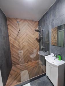 ein Bad mit einer Dusche und einer Holzwand in der Unterkunft ЖК Дрім Таун, район жд вокзала in Luzk