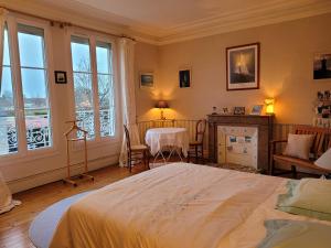a bedroom with a bed and a table and windows at chambres d'hôtes 