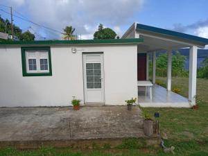 een wit huis met een veranda en een bank bij Bel'lune in La Trinité