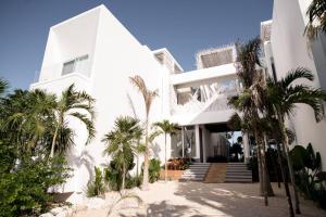 a white building with palm trees in front of it at TULUM Beachfront Villa I'Ik by Casa Xuul Tulum in Tulum