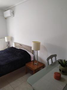 ein Schlafzimmer mit einem Bett und einem Tisch mit einer Lampe in der Unterkunft Tzikas apARTments in Thessaloniki