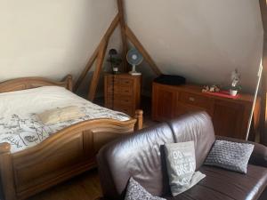 a bedroom with a bed and a leather couch at De oude paardentramremise in Ulrum