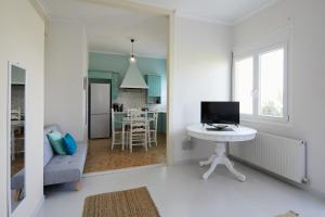 a white living room with a white table and a television at Mosaic Cosy House in Chios