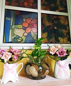 a group of vases and flowers in front of a window at New Garden View GF Double Room FREE parking in Batu Unjor