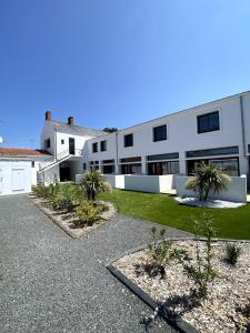 un gran edificio blanco con palmeras delante en Loft moderne avec terrasse en hyper centre-ville en Saint-Jean-de-Monts