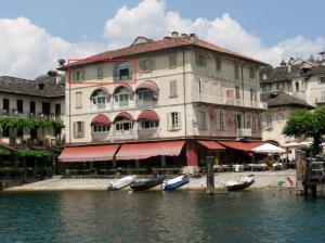 a large building with boats in front of it on the water at -Ortaflats- Appartamento l'Isola in Orta San Giulio