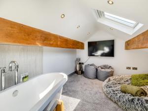 uma grande banheira branca num quarto com uma televisão em Squirrel Cottage em Glossop