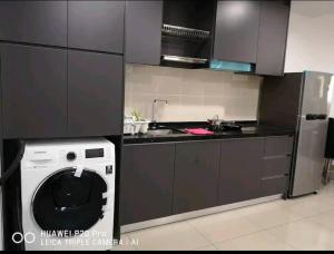 a kitchen with a washing machine and a refrigerator at Cozy 3 Guests High Floor at Puteri Harbour L22 in Nusajaya