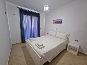 a white bedroom with a white bed and a window at Villa White in Ksamil