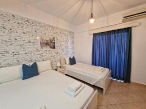 sypialnia z 2 łóżkami i ceglaną ścianą w obiekcie Villa White w mieście Ksamil