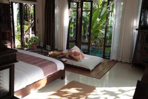 um quarto com uma cama, um sofá e janelas em KhgeMa NuanJun Pool Villa Gallery Resort em Ban Huai Yai