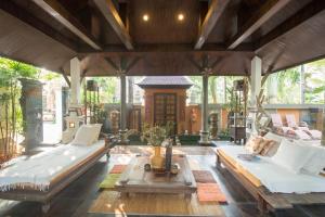 an outdoor living room with a couch and a table at KhgeMa NuanJun Pool Villa Gallery Resort in Ban Huai Yai