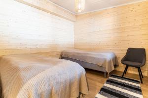 Habitación con 2 camas y una silla. en Näköalahuvila Pikku-Syötteen Helmi, en Syöte