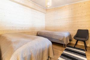 a room with two beds and a chair in it at Näköalahuvila Pikku-Syötteen Helmi in Syöte