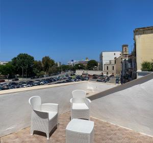 3 weiße Stühle auf einem Dach in der Unterkunft Nyx Dea Della Notte in Bari