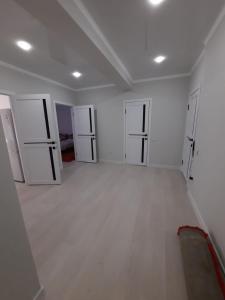 um quarto vazio com paredes brancas e quatro portas em Жк Сити плюс em Almaty