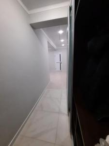 um corredor vazio com um piso branco e uma porta em Жк Сити плюс em Almaty