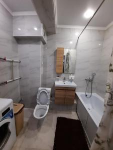 uma casa de banho com um WC, um lavatório e uma banheira em Жк Сити плюс em Almaty