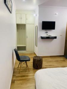 een slaapkamer met een stoel en een televisie aan de muur bij Mrig Valley Resort, Homestay & Banquet in Kandikhal