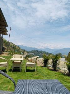 twee stoelen en een tafel op een grasveld bij Mrig Valley Resort, Homestay & Banquet in Kandikhal