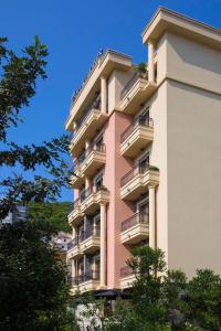 a tall pink building with balconies and trees at Hotel Vladimir in Budva