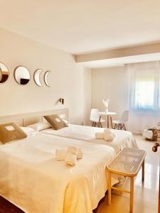a white bedroom with two beds and a table at Hostal Lóbrega in Torrecilla en Cameros