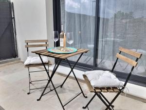 een tafel met een fles wijn en twee stoelen bij Appartement Balnéo in Villeneuve