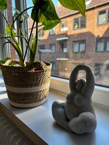 a couple of statues sitting on a window sill next to a plant at Großzügige 3-Zimmer Altbauwohnung in Kiel