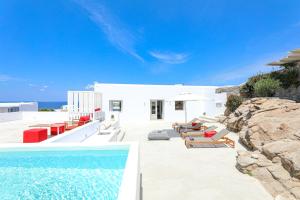 una villa con piscina e alcune sedie di O Lofos Luxury Boutique Suites ad Agios Stefanos