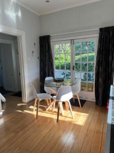a dining room with a table and chairs and a window at SHORT WALK TO NELSON CITY CENTRE - Quiet location, comfy beds, pet friendly, full kitchen, claw-foot bath tub, outdoor areas in Nelson